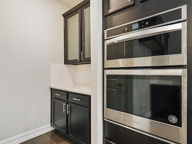 1722 Port Royal Ln, Frisco, TX 75036 - kitchen with double oven, baseboards, dark wood-style floors, and light stone counters
