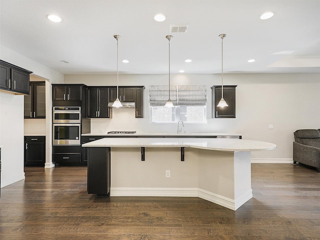 1722 Port Royal Ln, Frisco, TX 75036 - kitchen featuring double oven, under cabinet range hood, stovetop, a kitchen island, and light countertops