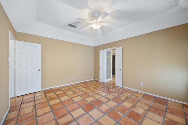 tiled spare room featuring visible vents, a ceiling fan, a textured ceiling, baseboards, and vaulted ceiling