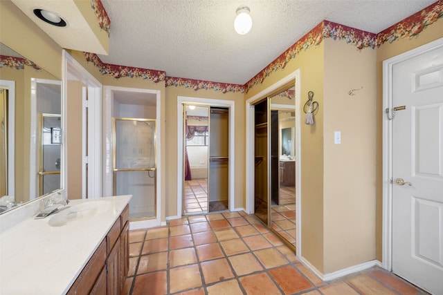 full bathroom with baseboards, a textured ceiling, a stall shower, and vanity