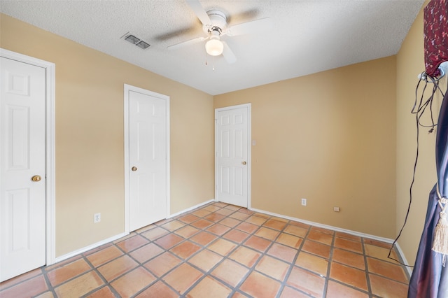 unfurnished bedroom featuring a ceiling fan, baseboards, visible vents, and a textured ceiling