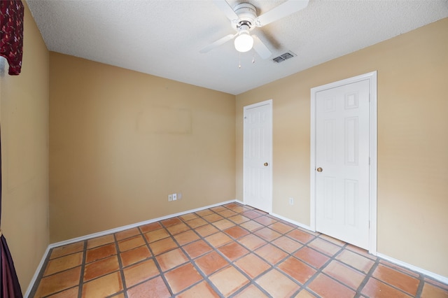 unfurnished bedroom with visible vents, a ceiling fan, a textured ceiling, light tile patterned floors, and baseboards