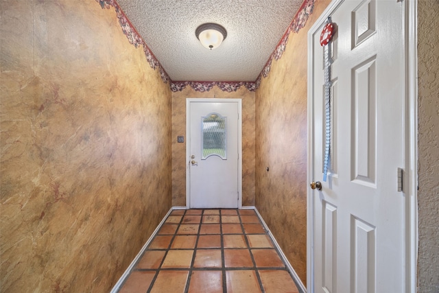doorway to outside with baseboards and a textured ceiling