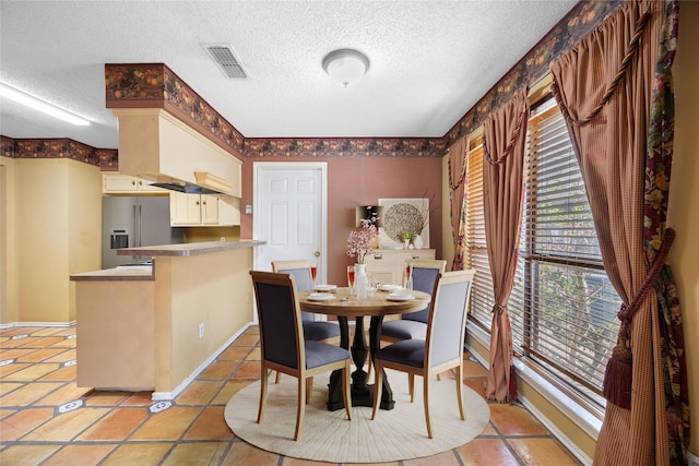 dining room featuring light tile patterned flooring, baseboards, visible vents, and a textured ceiling