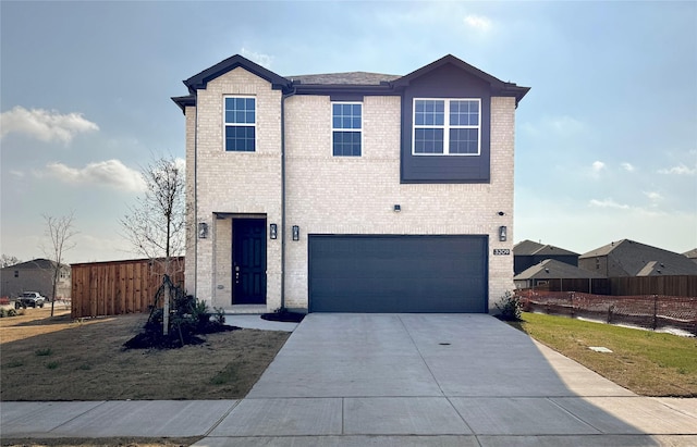 traditional-style home with brick siding, concrete driveway, an attached garage, and fence