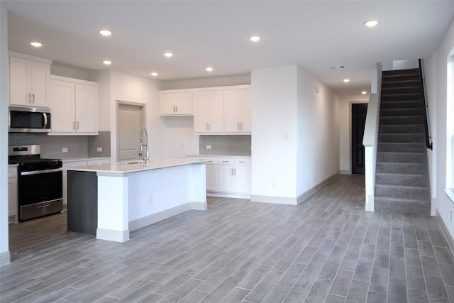 kitchen with a sink, stainless steel appliances, light wood-style floors, and recessed lighting