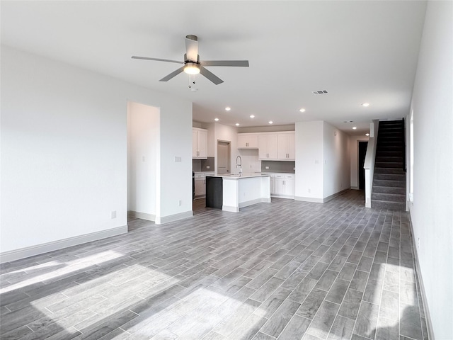 unfurnished living room with visible vents, stairway, a ceiling fan, and light wood-style floors