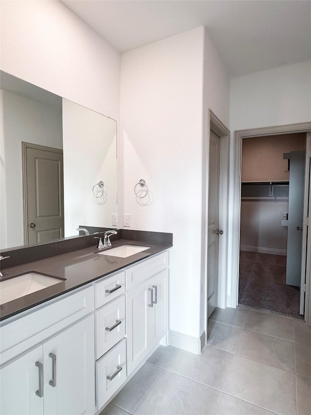 bathroom with tile patterned flooring, double vanity, baseboards, and a sink