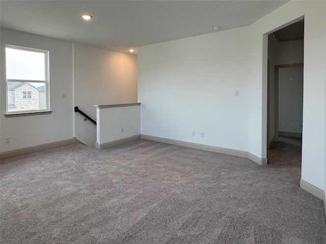 carpeted empty room with recessed lighting, attic access, and baseboards