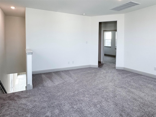 carpeted spare room with visible vents and baseboards