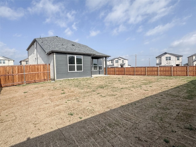 back of property featuring a fenced backyard and a shingled roof