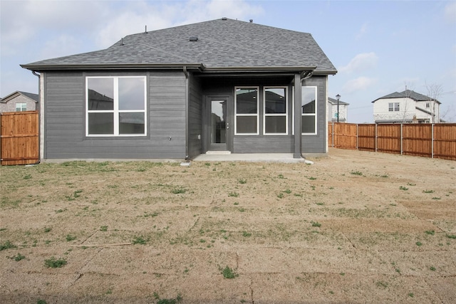 rear view of property featuring roof with shingles and a fenced backyard