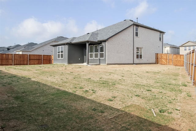 back of property with a lawn, a fenced backyard, and roof with shingles