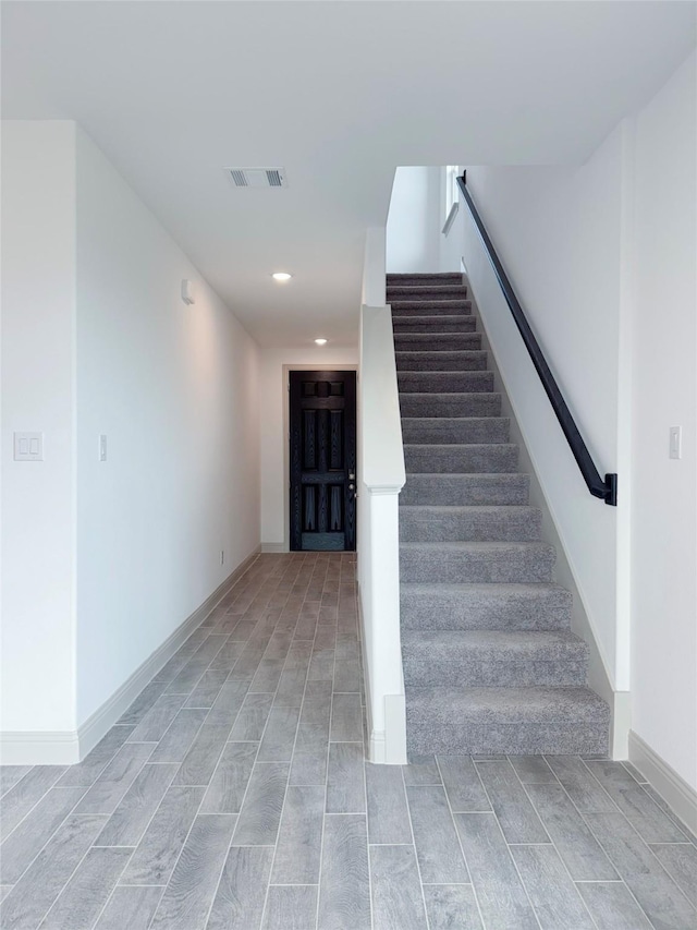 staircase with recessed lighting, visible vents, wood finish floors, and baseboards