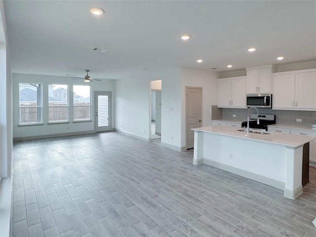 kitchen with white cabinetry, light countertops, light wood-type flooring, and stainless steel appliances