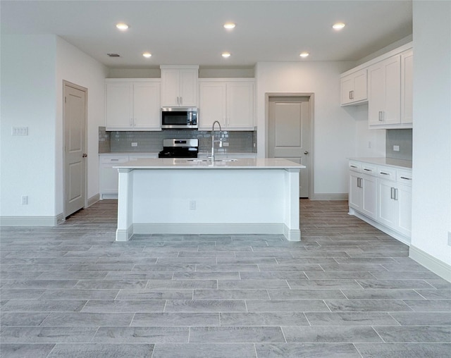 kitchen with a sink, stainless steel appliances, white cabinetry, and light countertops