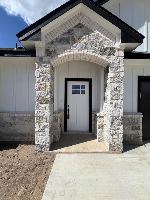 doorway to property with board and batten siding and stone siding