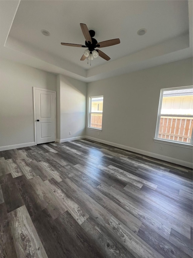 unfurnished room featuring baseboards, a ceiling fan, wood finished floors, and a tray ceiling