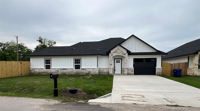 view of front of property featuring fence, concrete driveway, an attached garage, stone siding, and a front yard