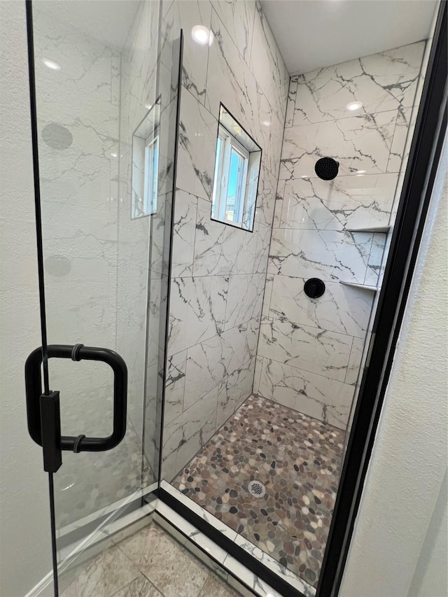 bathroom featuring a marble finish shower