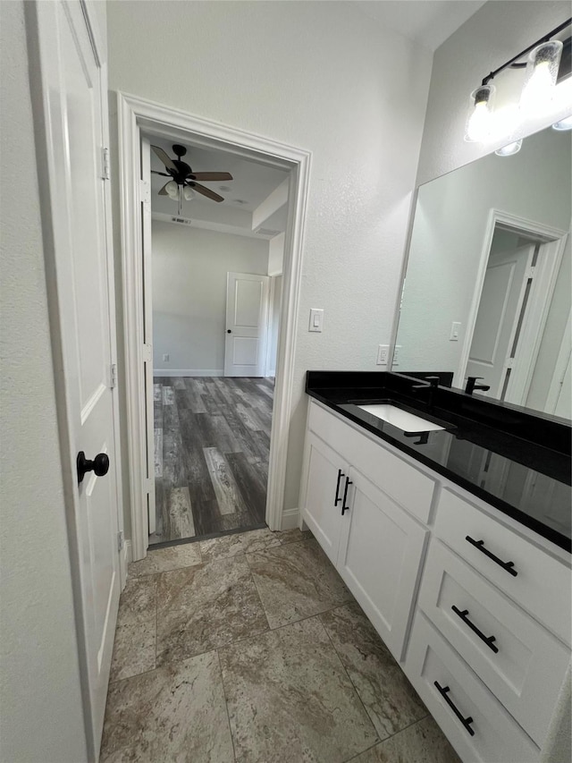 bathroom featuring baseboards, a ceiling fan, vanity, and stone finish floor