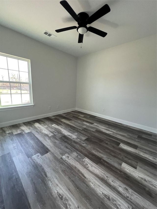 unfurnished room featuring baseboards, a ceiling fan, visible vents, and dark wood-style floors