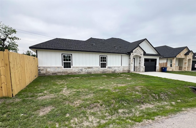 view of front of home with a front lawn, fence, stone siding, and driveway