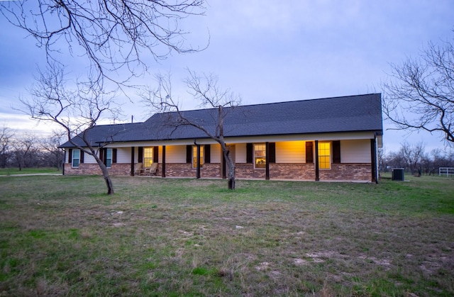 view of front of house featuring a front lawn, covered porch, and central AC