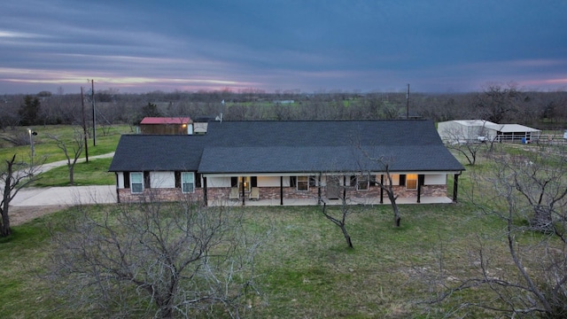 view of front of home featuring stone siding, covered porch, a shingled roof, and a front yard