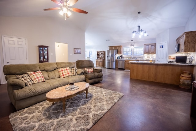 living room featuring vaulted ceiling, finished concrete flooring, and ceiling fan with notable chandelier
