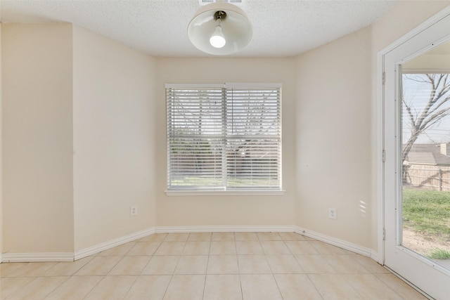 unfurnished room featuring a healthy amount of sunlight, baseboards, and a textured ceiling