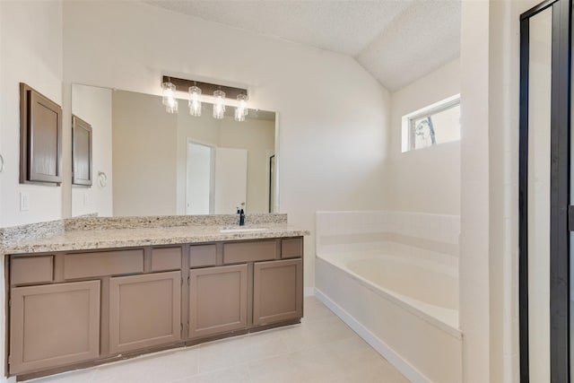 bathroom featuring tile patterned flooring, vanity, a garden tub, vaulted ceiling, and a textured ceiling