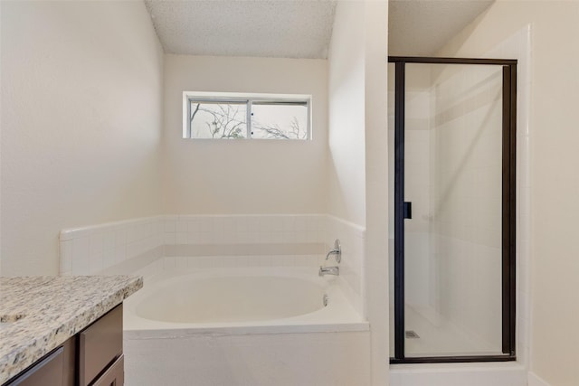 full bathroom featuring a stall shower, a textured ceiling, vanity, and a garden tub