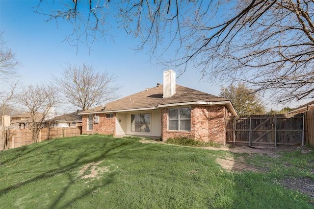 back of house featuring a gate, fence, a chimney, a lawn, and brick siding