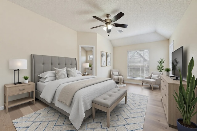 bedroom with ceiling fan, vaulted ceiling, light wood-style floors, and a textured ceiling