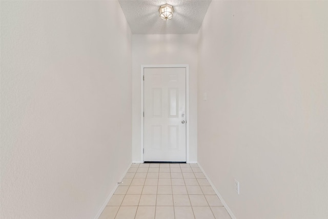 entryway with light tile patterned flooring, a textured ceiling, and baseboards