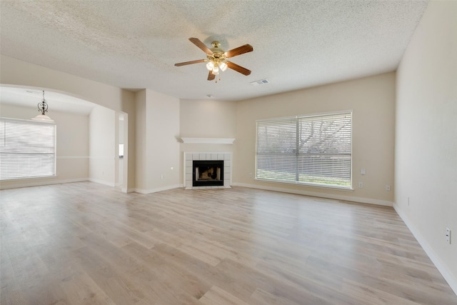 unfurnished living room featuring light wood-style floors, visible vents, a wealth of natural light, and ceiling fan