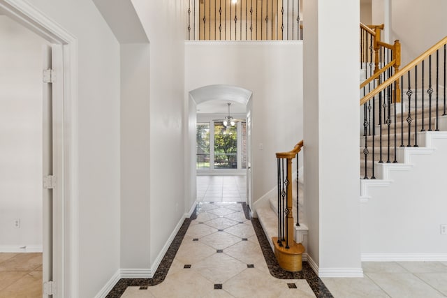 6976 Valley Brook Dr, Frisco, TX 75035 - corridor featuring arched walkways, inlaid floor details, a towering ceiling, tile patterned flooring, and stairs