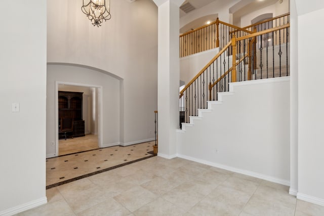 6976 Valley Brook Dr, Frisco, TX 75035 - foyer entrance featuring a high ceiling, arched walkways, stairs, inlaid floor details, and tile patterned flooring