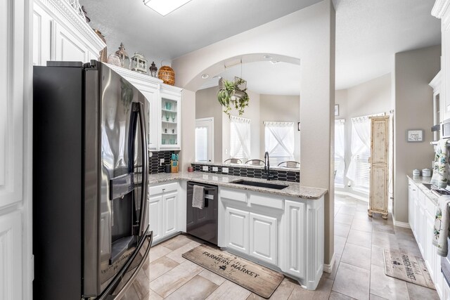 kitchen featuring white cabinetry, arched walkways, a sink, dishwasher, and stainless steel fridge