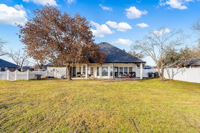 rear view of property featuring a patio area, a yard, and a fenced backyard