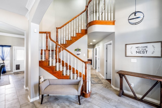 staircase featuring baseboards and a high ceiling