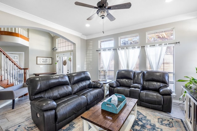 living area featuring a ceiling fan, crown molding, a healthy amount of sunlight, and arched walkways