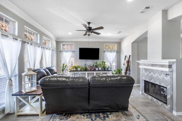living room featuring visible vents, ceiling fan, crown molding, and a tile fireplace