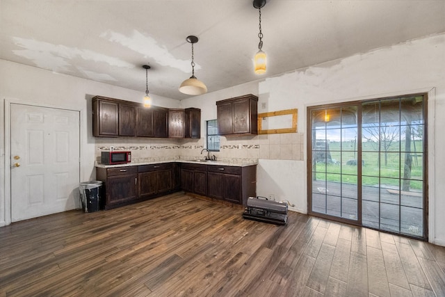 kitchen with a sink, dark wood-style flooring, dark brown cabinets, backsplash, and light countertops