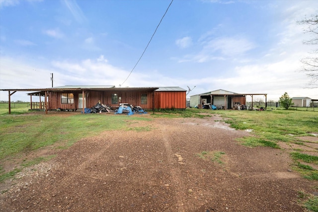 rear view of house with an outdoor structure, driveway, an outbuilding, and a detached garage