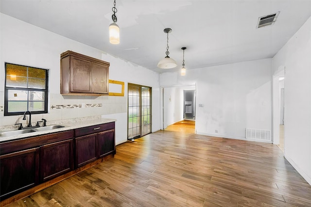 kitchen with light wood-type flooring, light countertops, visible vents, and a sink