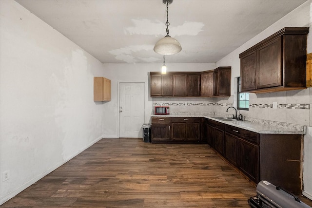kitchen featuring dark brown cabinetry, a sink, dark wood-type flooring, and light countertops