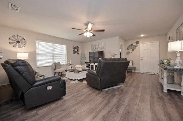 living room with a ceiling fan, dark wood-style floors, visible vents, and baseboards