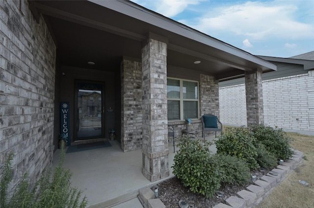 doorway to property featuring brick siding and covered porch